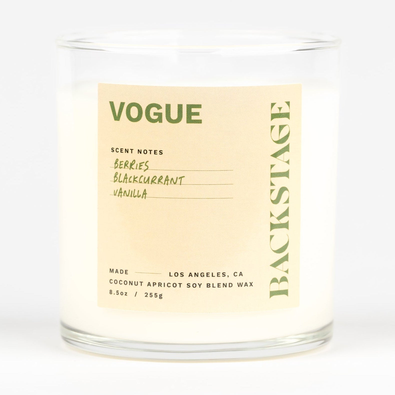 A white candle jar with the label 'VOGUE' on it, indicating the scent of the candle.